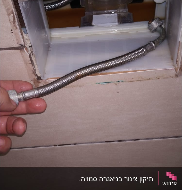 יד מחזיקה צינור גמיש ליד קיר פתוח
